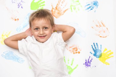 Küçük sarışın çocuk açık arkaplanda yüz ifadeleri gösteriyor.