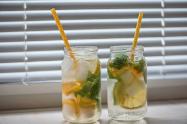 Limonlu, turuncu buzlu, hafif arka planda, yüksek anahtarlı alkolsüz yaz içeceği. 