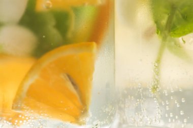 Limonlu, turuncu buzlu, hafif arka planda, yüksek anahtarlı alkolsüz yaz içeceği. 