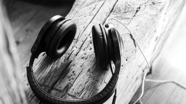 Müzik için büyük siyah kulaklıklar ahşap bir yüzeyde yatar.  
