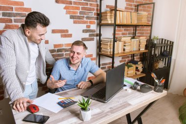 Ofiste uzaktan çalışan iki genç adam, masa başında çalışan, belgelerle çalışan, işi tartışan, duygusal olarak düşünen, işten sonra ve işten sonra yorgun iki genç adam.