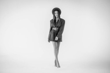 Çekici bir genç kız, gri ceketli bir manken ve elinde bir şapka tutuyor. Erkek tarzı kıyafetler. Beyaz bir arka planda izole edilmiş. Kenarında bir yazı için bir yer var. Seçici odak