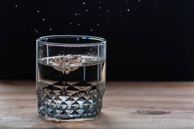 Dökülen suyla dolu bardaklar, ahşap bir masanın üzerine dökülen suyla şeffaf.