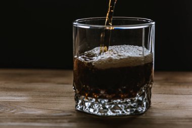 Koyu renk kenar görüşlü bir bardak, içecekten köpük ve su sıçraması. Seçici odak