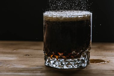 Koyu renk kenar görüşlü bir bardak, içecekten köpük ve su sıçraması. Seçici odak
