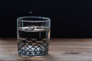 Dökülen suyla dolu bardaklar, ahşap bir masanın üzerine dökülen suyla şeffaf.