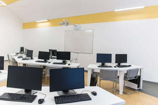 office room with computer tables with keyboard and mouse with a board and a projector 