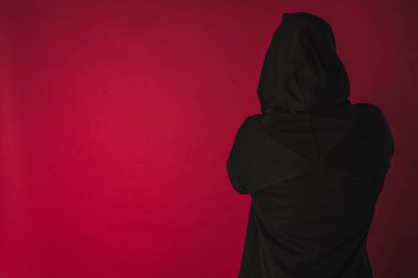 Sırtını siyah bir cekete sarmış ve kırmızı arka planda izole edilmiş bir kapüşonu var. Güçlü insanlar kavramı