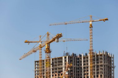 Mavi gökyüzüne karşı vinçleri olan inşaat alanı