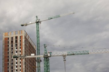 Bulutlu gökyüzüne karşı vinçleri olan inşaat alanı