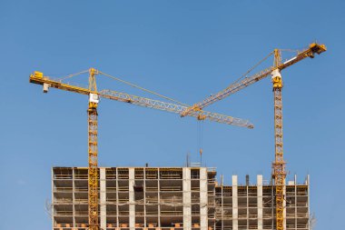 Mavi gökyüzüne karşı vinçleri olan inşaat alanı