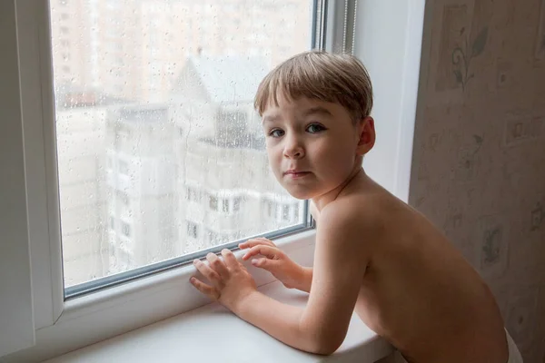 little boy watching the rain through the window. close-up