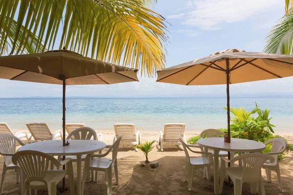 Tables de restaurant et chaises longues sur la plage Image En Vente