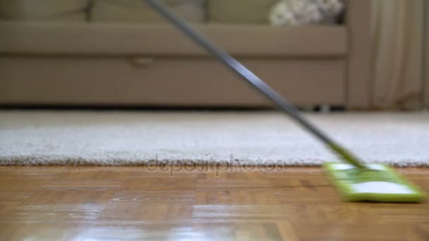 Mujer limpiando suelos de parquet en la sala de estar. Primer plano . — Vídeo de stock