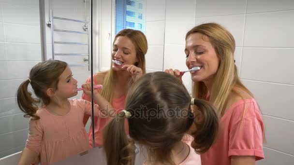 Unga attraktiva mamma och hennes söta dotter borsta sina tänder. Slow motion, — Stockvideo