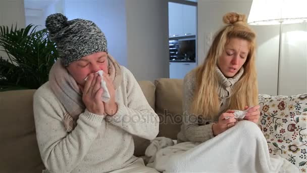 Par com febre e nariz escorrendo espirra em voz alta sentado na sala de estar . — Vídeo de Stock