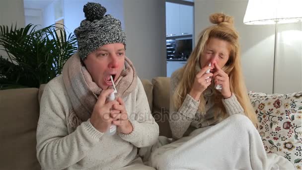 Zieke paar met loopneus met behulp van neus en keel Spray zit In woonkamer. — Stockvideo