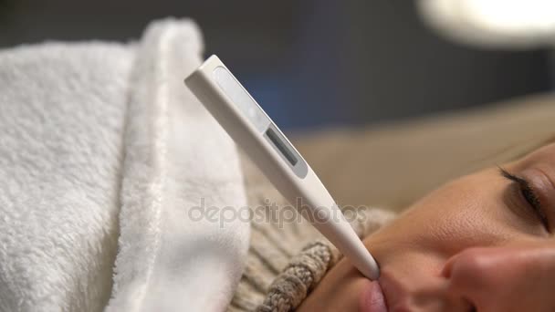 Una mujer con fiebre acostada en el sofá con termómetro en la boca. Dolly. — Vídeos de Stock