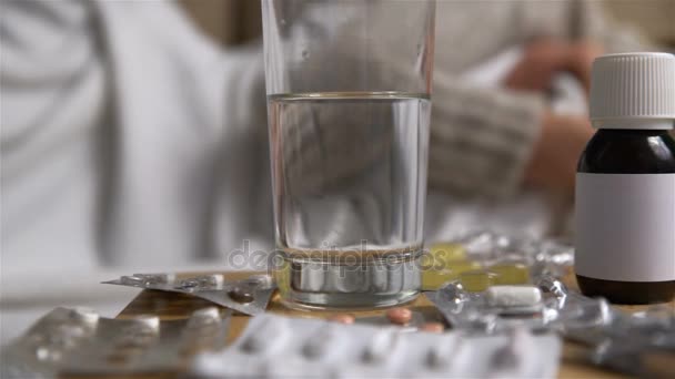 Egy csomó tabletták és gyógyszerek, egy asztal, egy beteg fiatal nő a kanapé előtt. Dolly lövés — Stock videók