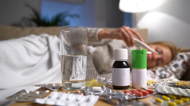 大量的药丸和前面的一个生病的年轻女子坐在沙发上的药品。多莉开枪 — 图库视频影像