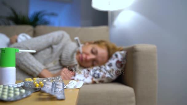 Tabletten und Medikamente auf einem Tisch vor einer kranken jungen Frau auf der Couch — Stockvideo