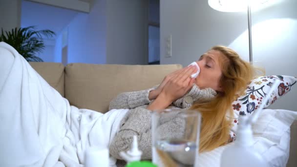 Una mujer con fiebre usa aerosol nasal y estornuda . — Vídeo de stock