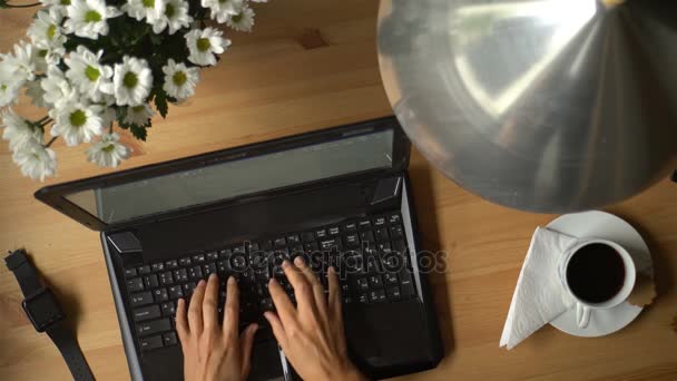 Een vrouw werkt op Computer met koffie en een boeket bloemen op tafel. — Stockvideo