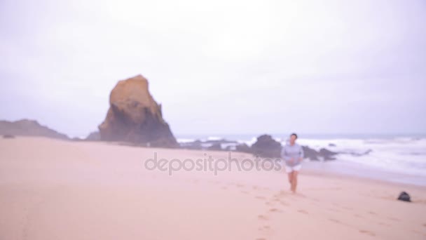 Atractiva mujer madura activa corriendo a lo largo de la playa del océano y sonriendo a la cámara . — Vídeo de stock