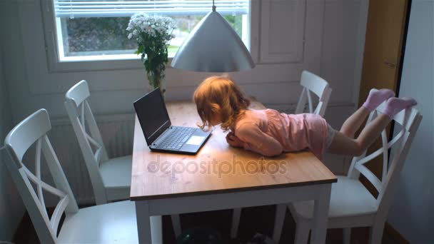Meisje enthousiast kijken cartoons op de laptop liggen op tafel. — Stockvideo