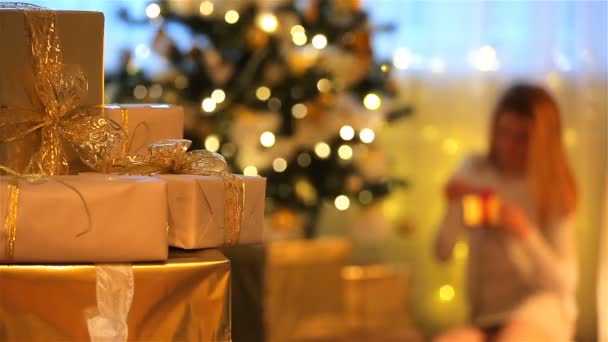 Christmas theme. Presents, lights, tree, young woman opens gifts. — Stock Video