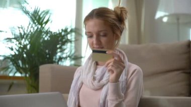 Güzel bir genç kadın altın kredi kartı online katta oturan kullanır. Dolly atış.