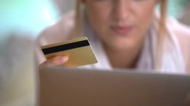 Genç kadın bir altın kredi kartı Online kanepede yatan kullanır. Dolly atış.
