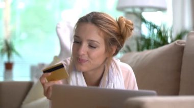 Genç kadın bir altın kredi kartı Online kanepede yatan kullanır. Ağır çekim