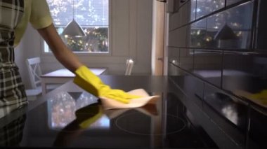 Ev kadını özel bir temizlik bezi ile elektrikli Ocak yüzeyi siliyor. Dolly.
