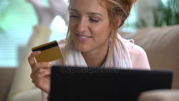 Jonge vrouw maakt gebruik van een gouden creditcard Online liggend op de Bank. Slow motion — Stockvideo