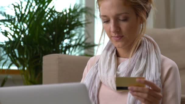 Μια όμορφη νεαρή γυναίκα χρησιμοποιεί χρυσή πιστωτική κάρτα online κάθεται στο πάτωμα. — Αρχείο Βίντεο