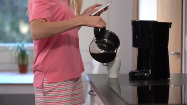 Una donna felice in pigiama, che balla in cucina, caffè, cuffie, smartphone — Video Stock