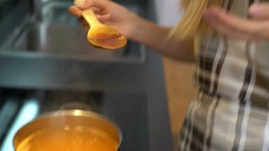 Hazırlama ve mutfakta yemek tatma mutlu genç ev hanımı.