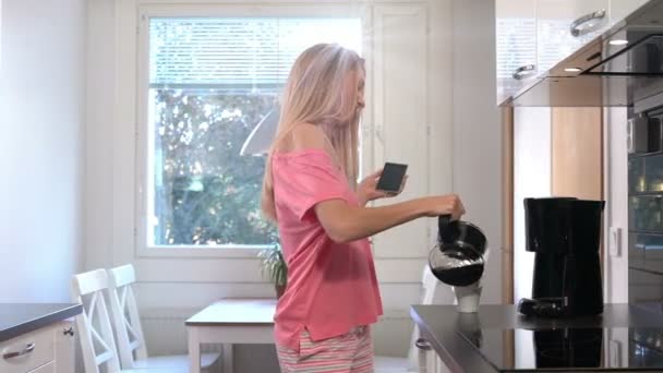 Una mujer feliz en pijama, bailando en la cocina, café. Dolly. Movimiento lento — Vídeo de stock