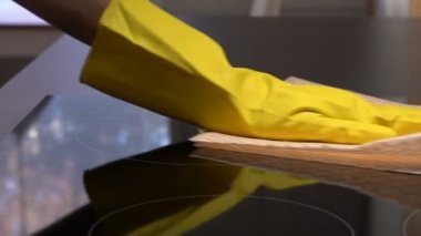 Ev kadını özel bir temizlik bezi ile elektrikli Ocak yüzeyi siliyor. Dolly. Ağır çekim