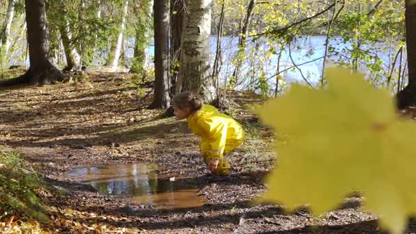 Liten flicka i gul gummi passar är att hoppa i en vattenpöl. Slow Motion — Stockvideo