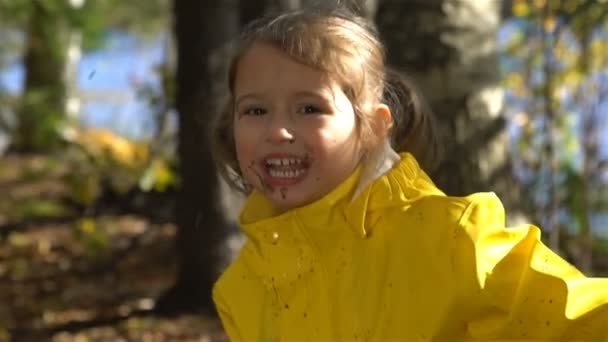 Petite fille drôle avec un visage sale saute dans la flaque sale. Mouvement lent .