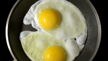 İki yumurta bir tencerede kızartılır. Zaman atlamalı. Zoom. Kamera dönme. Üstten Görünüm.
