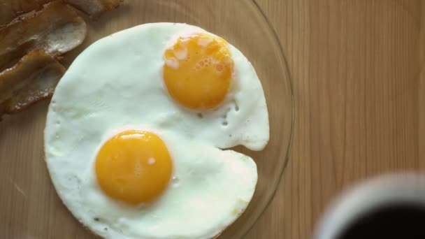 Ontbijt van koffie, spek en eieren op een houten tafel. Bovenaanzicht. — Stockvideo