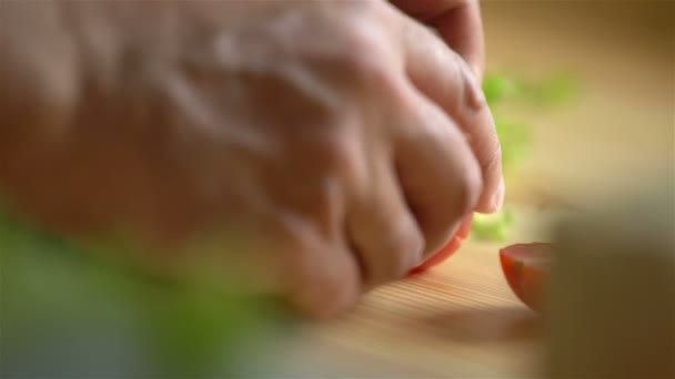 Γκρο πλαν. Ανδρικά χέρια κόβουμε την ντομάτα σε μια ξύλινη επιφάνεια. — Αρχείο Βίντεο