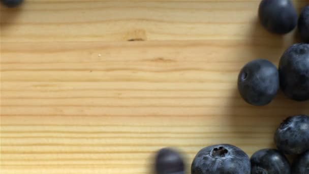 Many blueberries rolling on wooden surface. Slow motion. Top View. — Stock Video