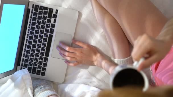 Женщина в пижаме сидит в постели с ноутбуком и пьет кофе. Slow Motion — стоковое видео