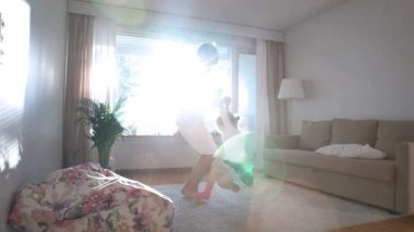 Baba döner ve güneşli odada ellerinde küçük kızı yukarı atar. Ağır çekim