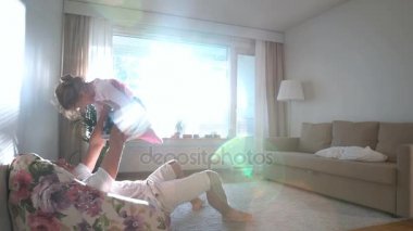 Baba döner ve güneşli odada ellerinde küçük kızı yukarı atar. Ağır çekim