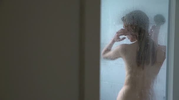 Jeune femme mince prenant une douche et se lavant les cheveux. Dolly Shot — Video